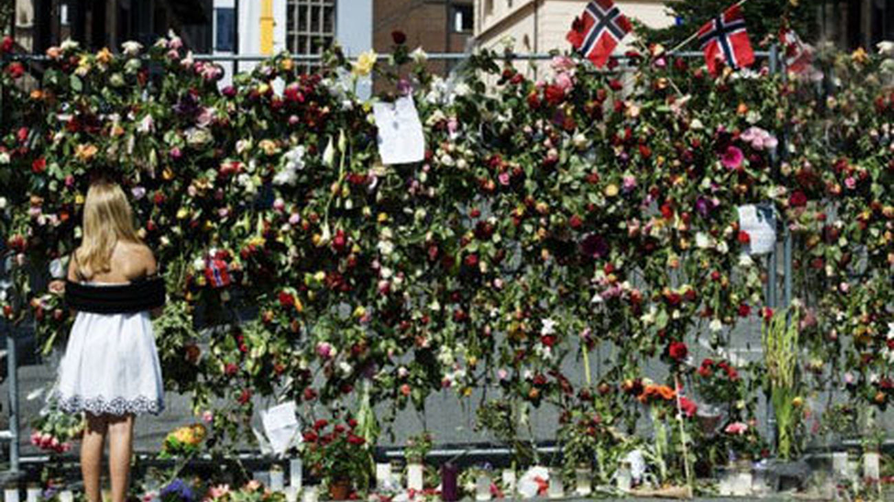 Una joven deposita flores en el muro conmemorativo a las víctimas de los atentados en Noruega