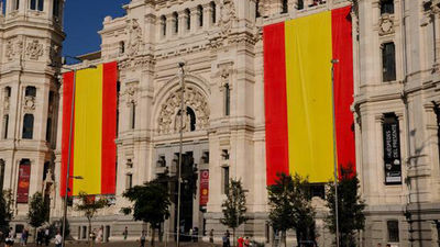 Dos banderas gigantes de España cubren la fachada del Ayuntamiento en Cibeles