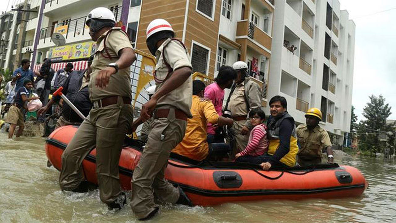 Bomberos y miembros de los servicios de emergencia indios evacúan a personas afectadas por las inundaciones