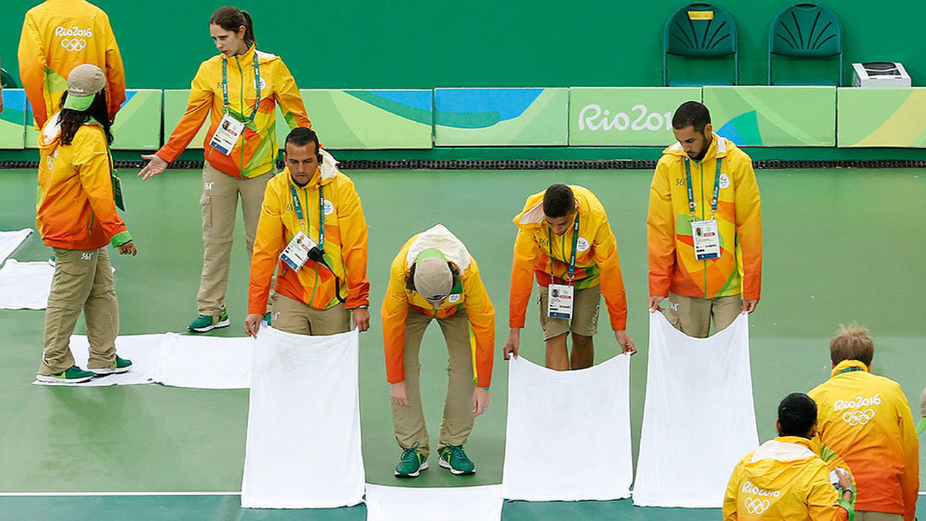 Voluntarios de Río 2016 intentan secar el agua que hacía impracticable las pistas de tenis