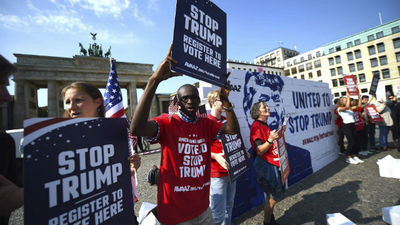 Activistas levantan y derriban el muro de Trump ante la Puerta de Brandeburgo