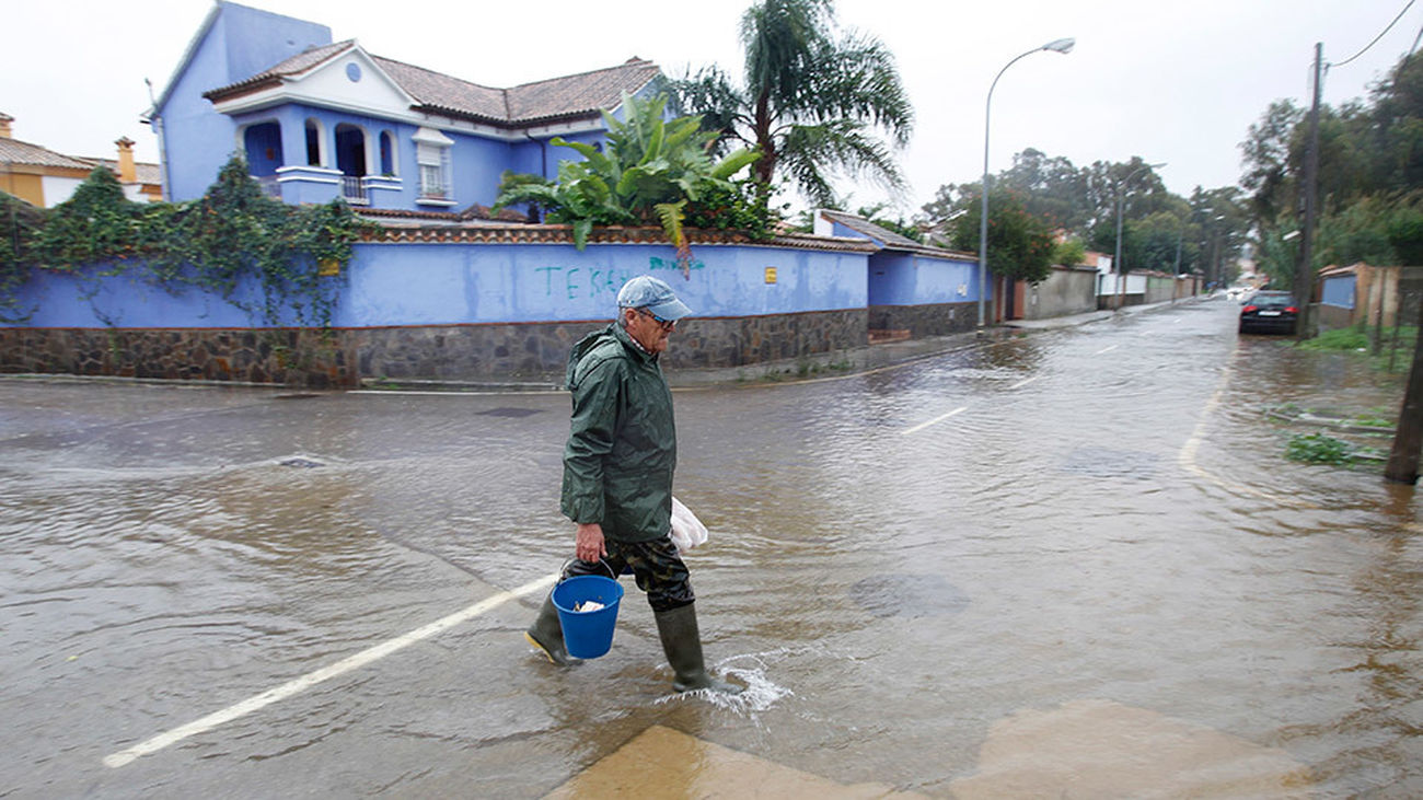 Un vecino cruza una calle inundada en la urbanización de Guadacorte en Los Barrios (Cádiz), tras el temporal en las provincias