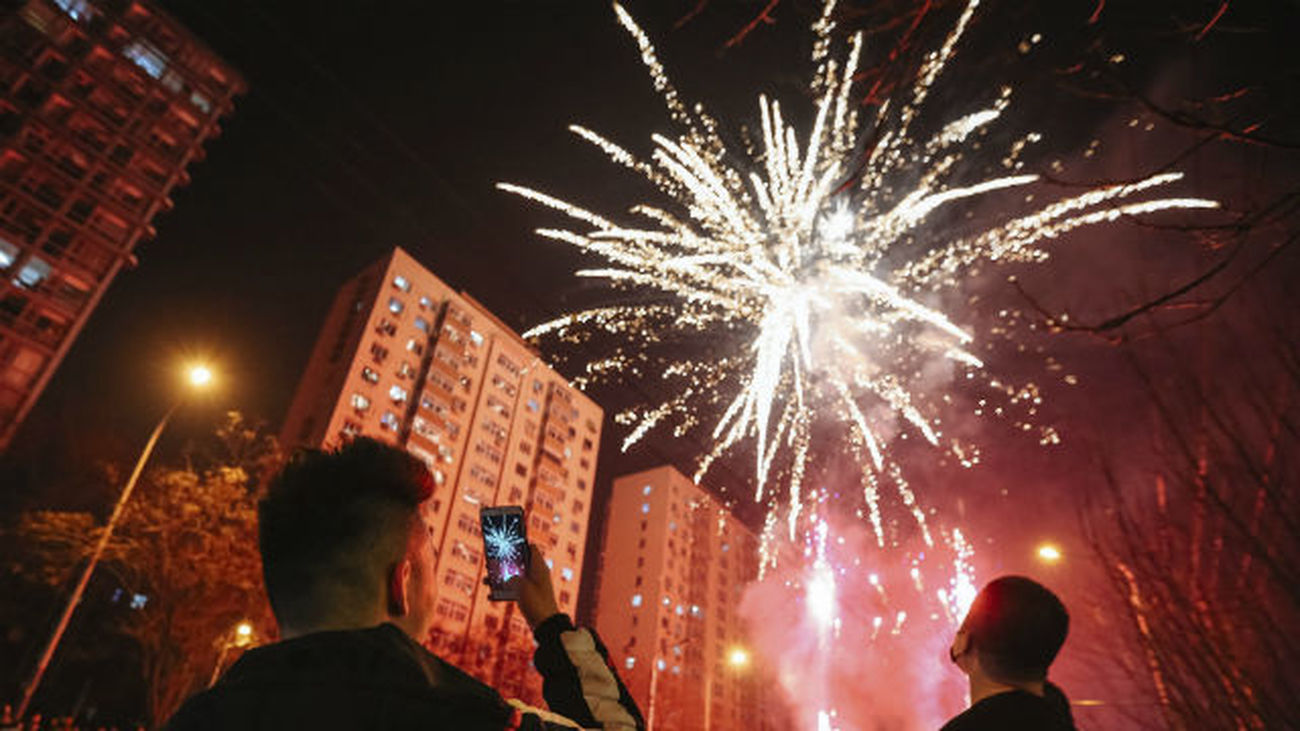 Un hombre hace una fotografía a los fuegos artificiales que lucen el cielo de Pekín