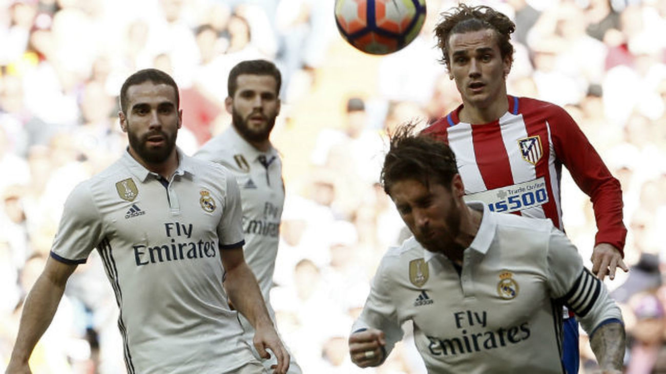 El defensa del Real Madrid Sergio Ramos despeja ante el delantero francés del Atlético de Madrid, Antoine Griezmann