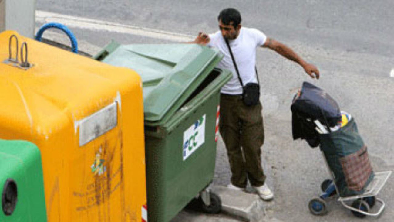 Un hombre busca comida en un cubo de basura