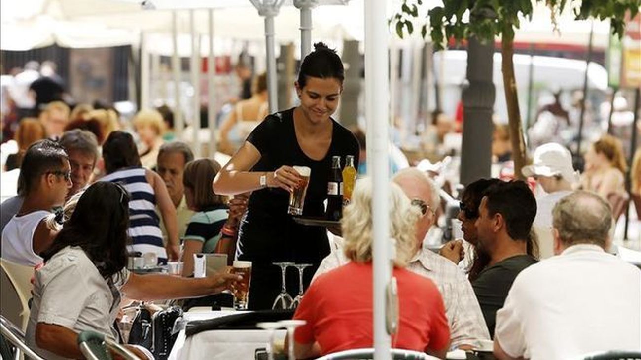 Una camarera sirve a unos turistas en la terraza de un restaurante