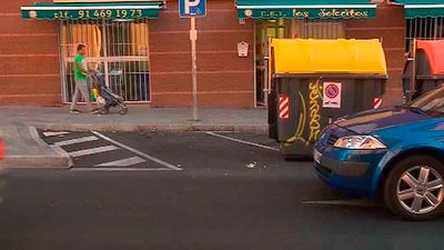 Un contendor municipal junto a una plaza de discapacidad