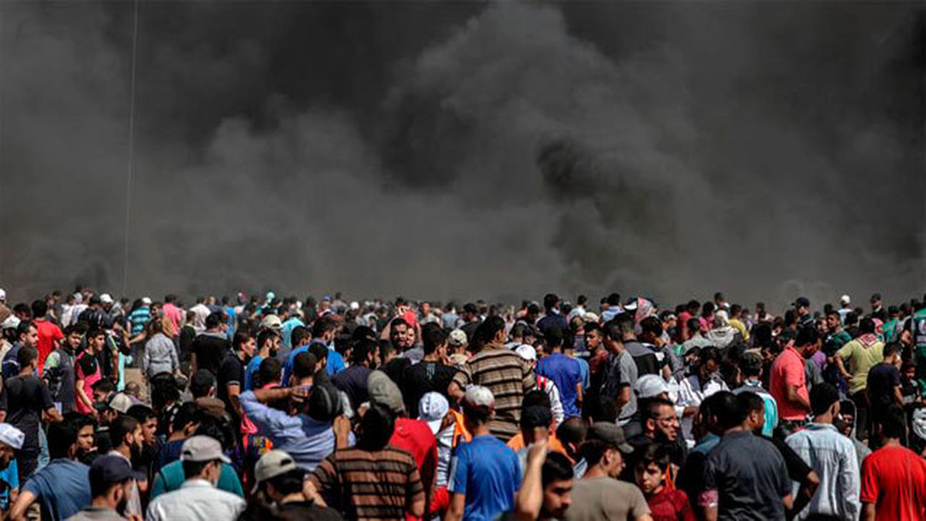 Cientos de palestinos observan las cápsulas de gases lacrimógenos lanzadas por Israel hacia los territorios palestinos en Gaza