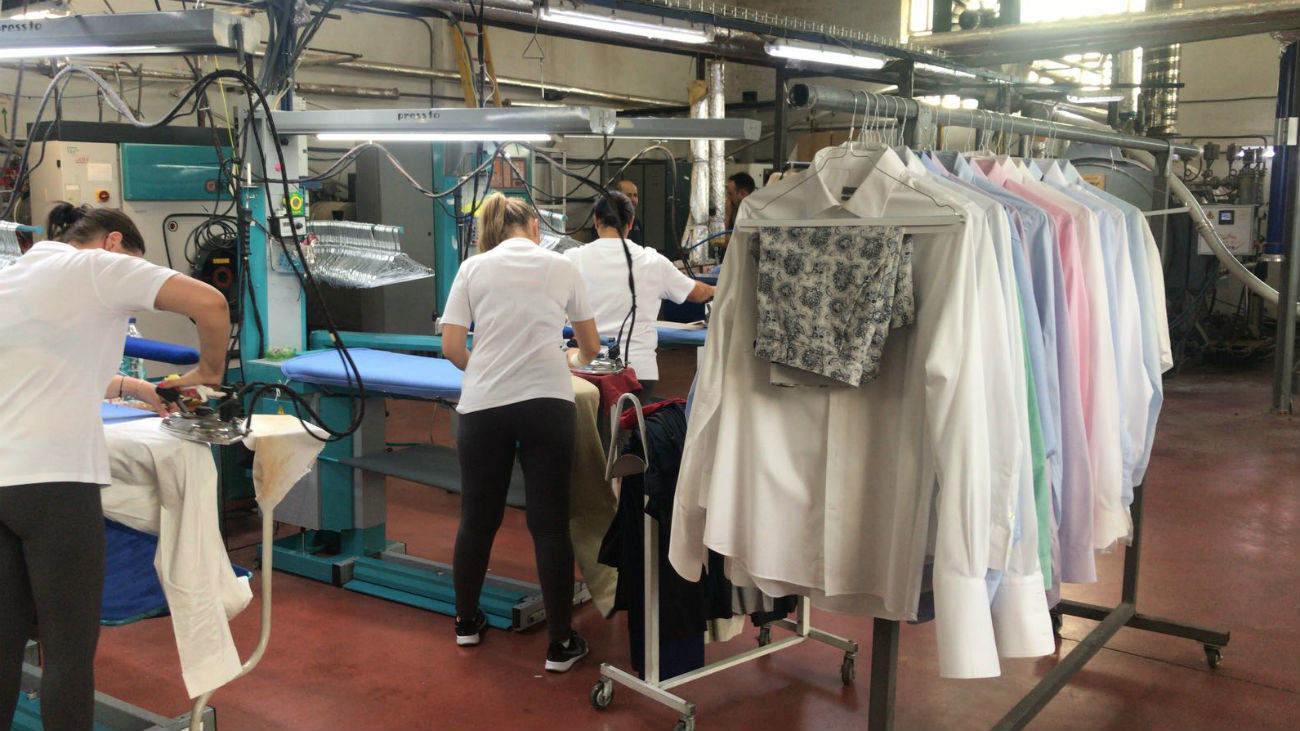 Empleados realizando labores de planchado en la tintorería