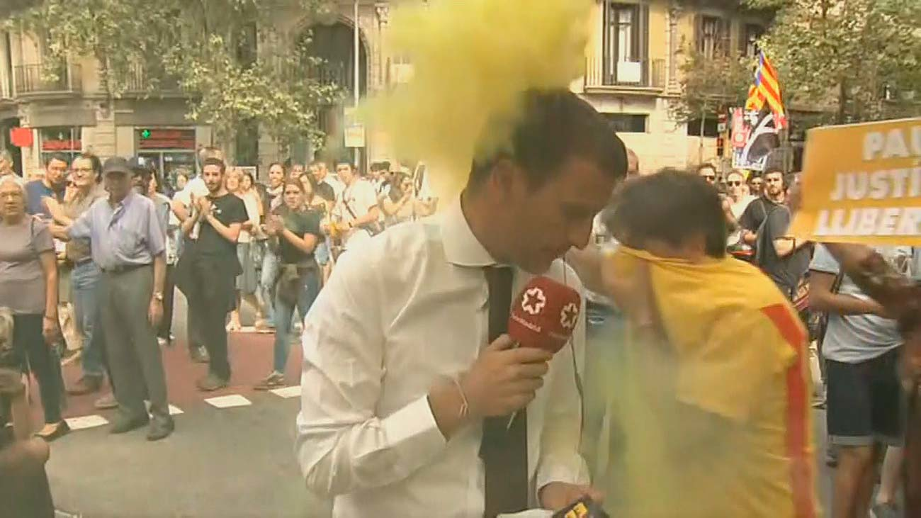 Un reportero de Telemadrid interrumpe su conexión por un bote de humo encendido durante la manifestación del 1-O