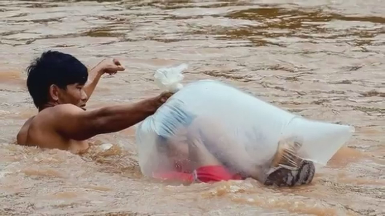 Niños en bolsas de plástico para cruzar un río e ir al colegio en Vietnam