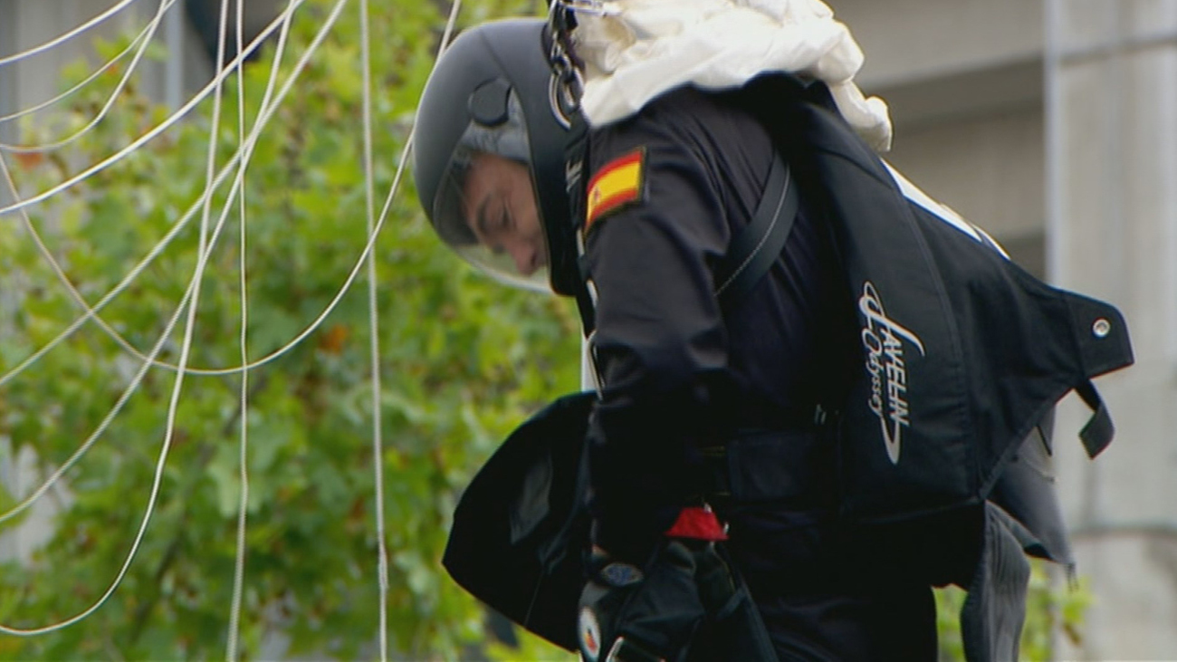 El paracaidista que porta la bandera se engancha en una farola