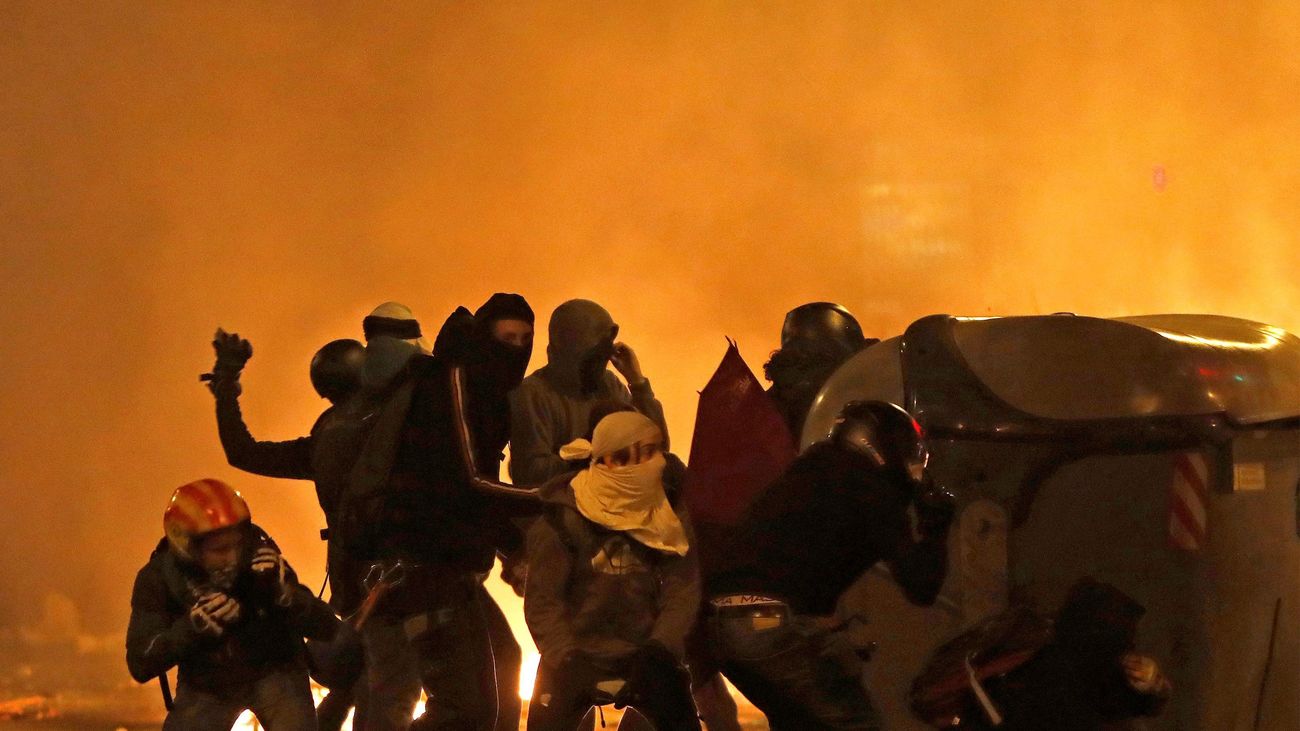 Manifestantes radicales se ocultan detrás de un contenedor