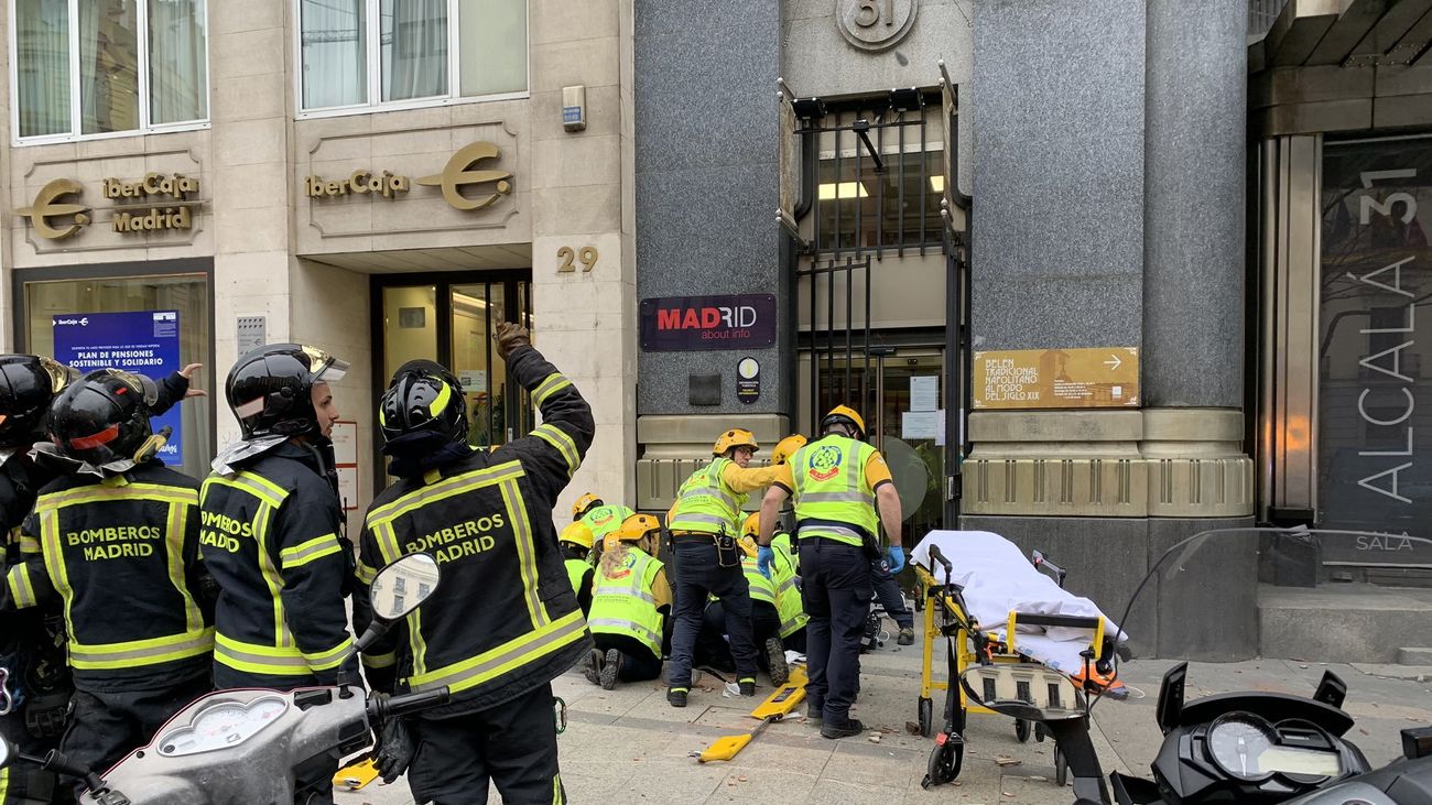 Sanitarios atienden a la mujer coreana que finalmente falleció tras recibir el impacto de unos cascotes en la calle Alcalá