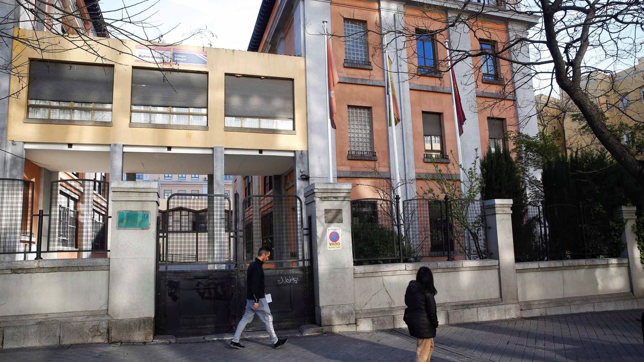 Dos personas caminan ante un colegio vacío en Madrid por culpa del coronavirus