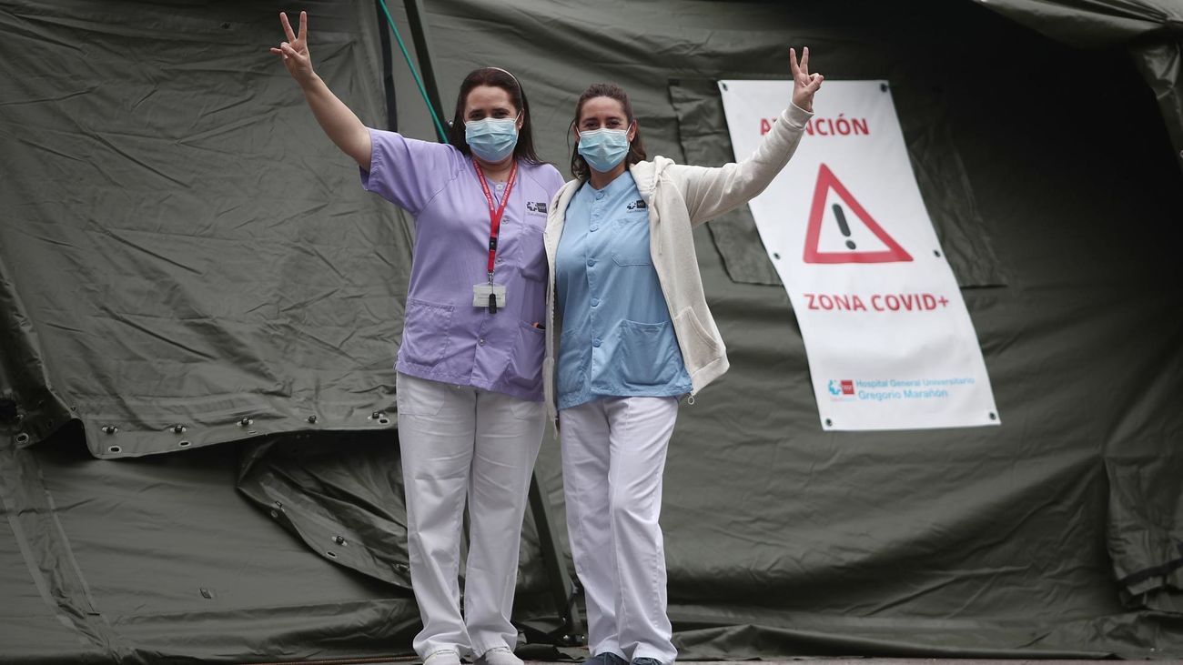 Dos sanitarias saludan frente al hospital de campaña instalado junto al Gregorio Marañón