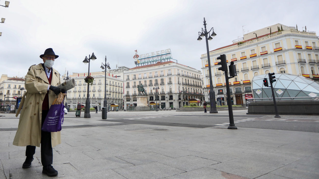 Un hombre camina protegido con guantes y mascarilla por la Puerta del Sol, prácticamente desierta