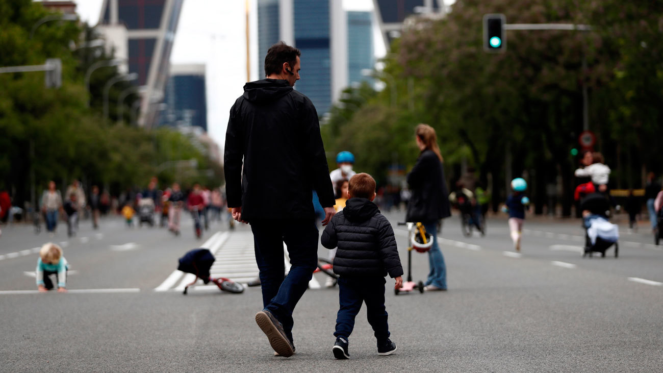 Un hombre pasea a su hijo en el Paseo de la Castellana