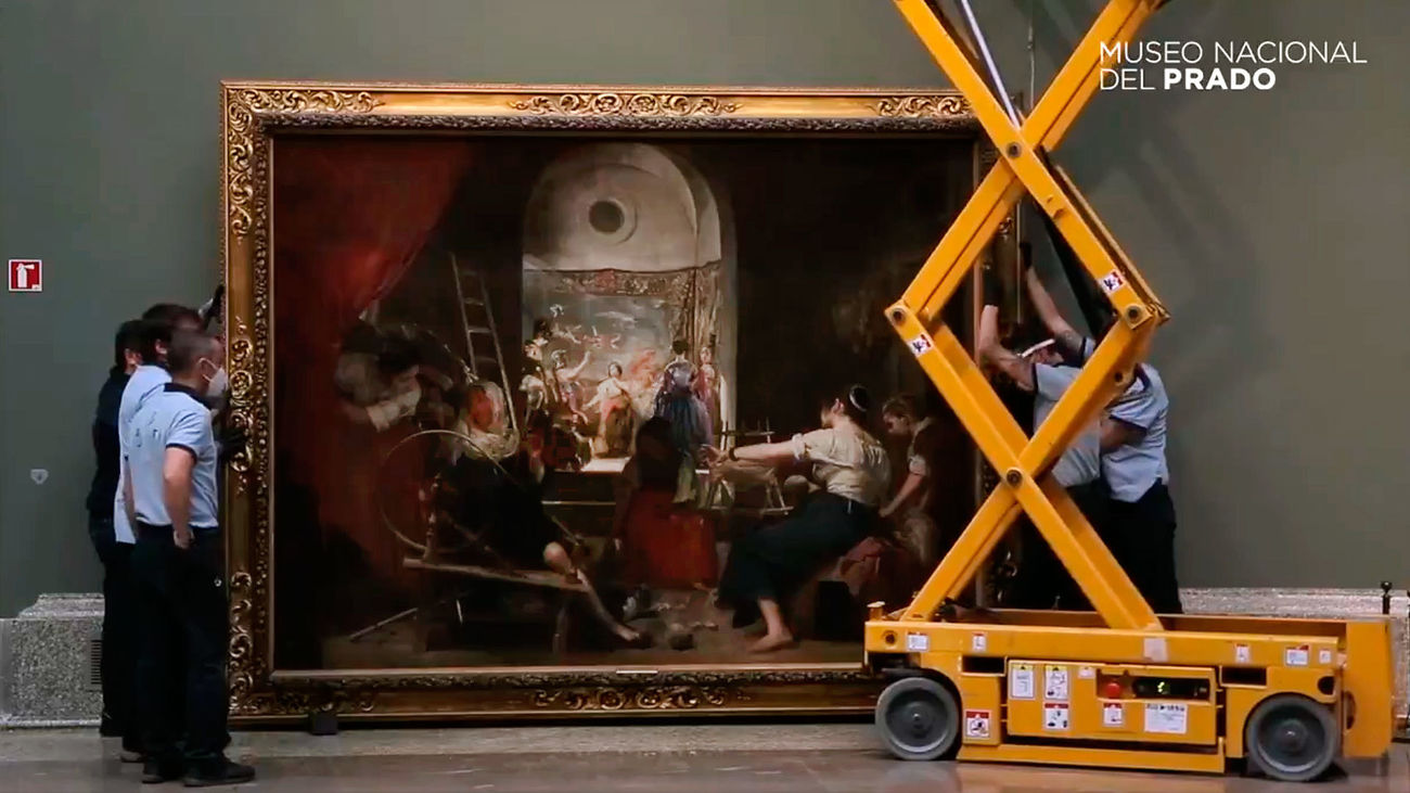 Personal del Museo del Prado colocando 'Las Hilanderas' de Velázquez para la exposición de reapertura tras el cierre temporal por la covid-19