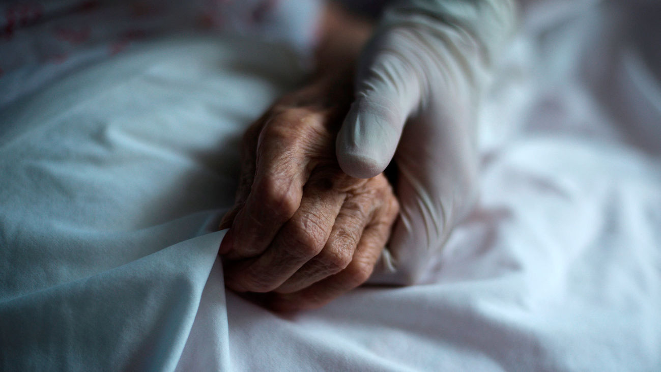 Un cuidador coge la mano de una anciana en una residencia de mayores