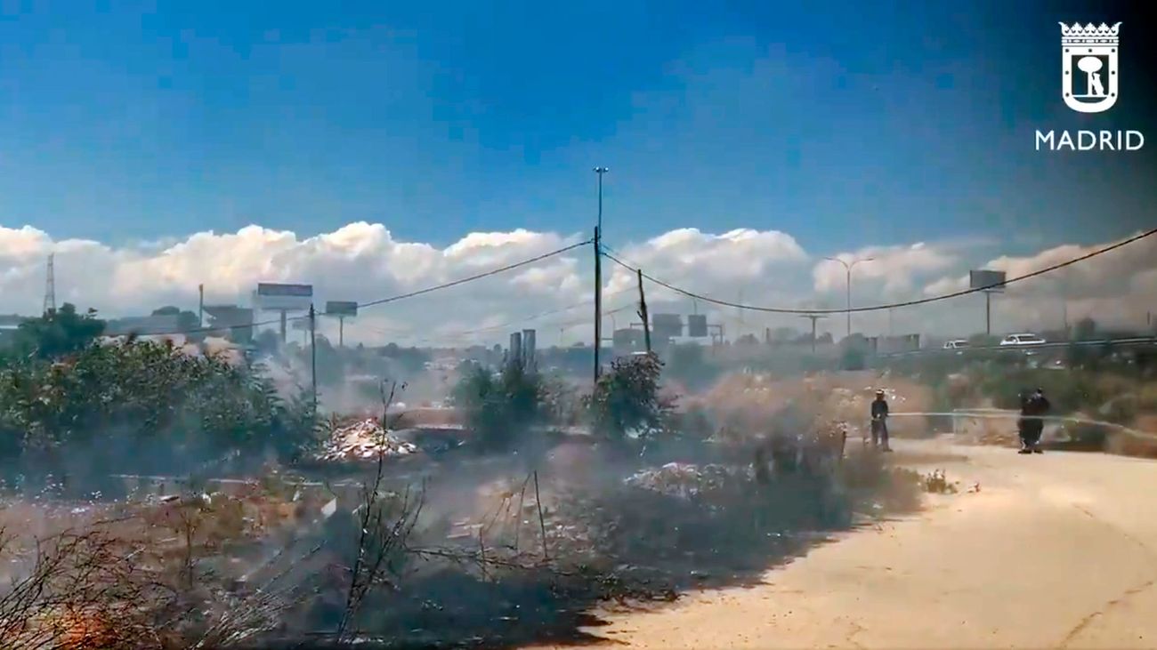 Los bomberos trabajan en un incendio de pastos en el poblado del Gallinero