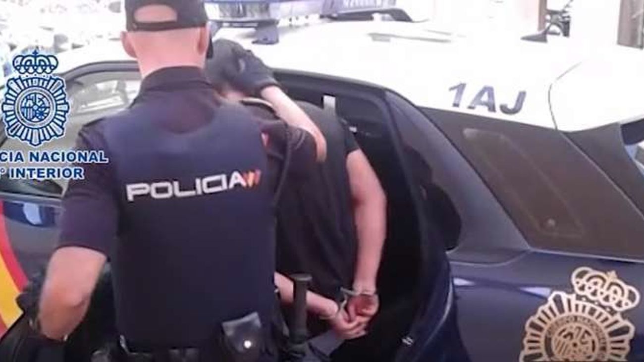 Un agente de la Policía Nacional conduce a un detenido