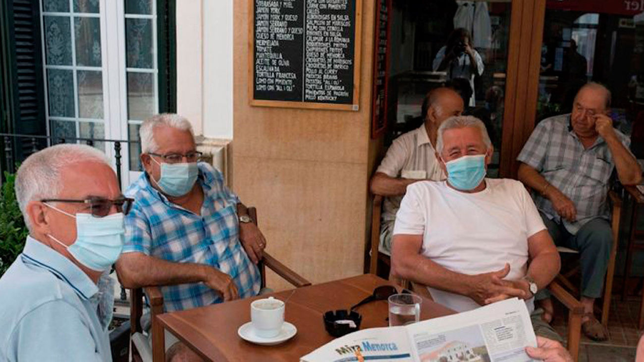 Un grupo de personas con mascarillas toma el café en la terraza de un bar