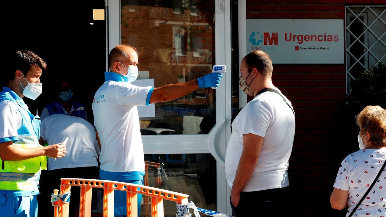 Un paramédico toma la temperatura a un ciudadano antes de acceder al centro de salud Reyes Católicos, de la localidad madrileña San Sebastián de los Reyes.