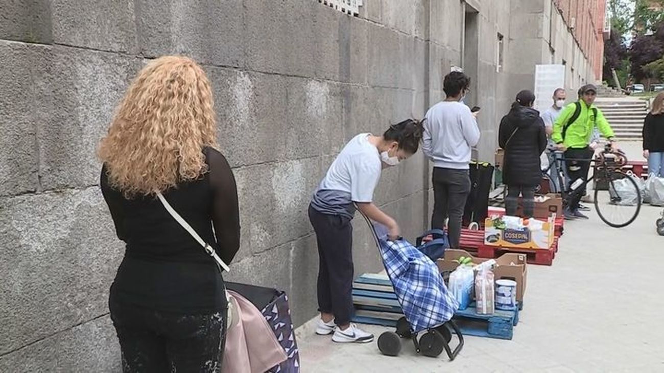 Fila de personas esperando para recibir alimentos en un barrio de Madrid