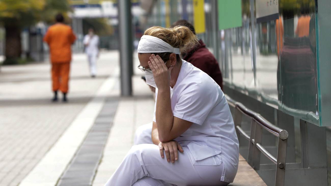 Una trabajadora sanitaria protegida se sienta en uno de los bancos de las inmediaciones del hospital de campaña montado en Ifema