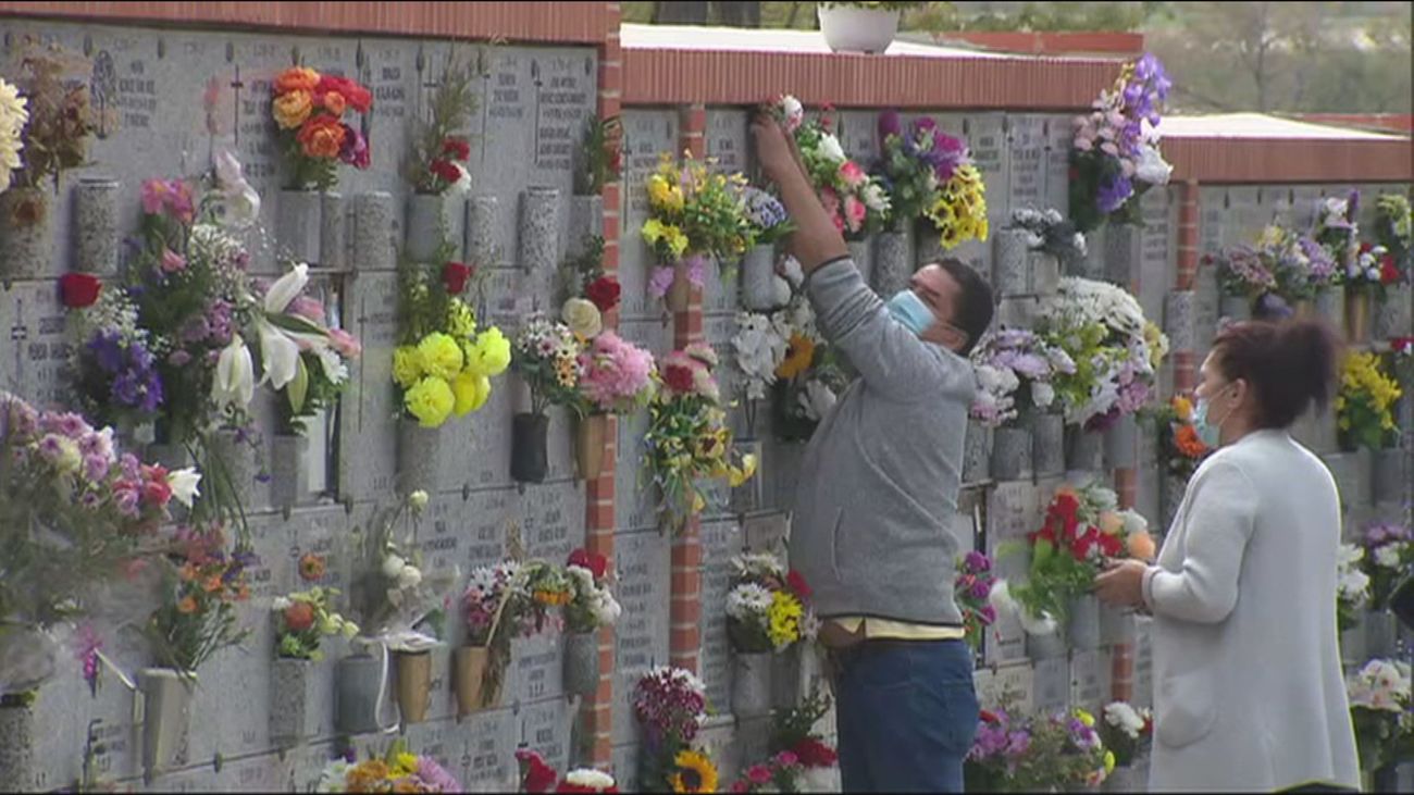 Unos visitantes ponen flores a sus familiares en el cementerio de La Almudena