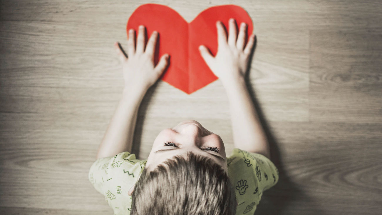 Un niño sostiene un corazón rojo