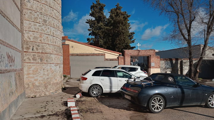 Vehículos aparcado junto al ábside del templo y algunas pintadas en el muro / P.O.