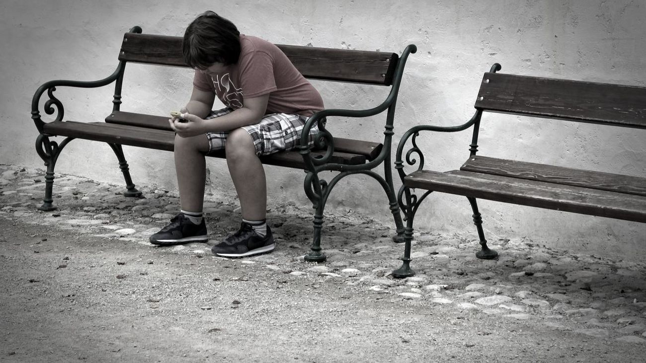 Un adolescente juega con su teléfono en un parque