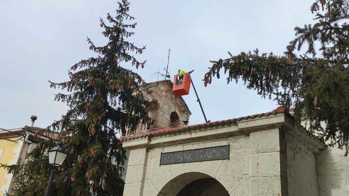 Un operario del Ayuntamiento de Pinilla de Buitrago, sobre la iglesia del municipio / TELEMADRID