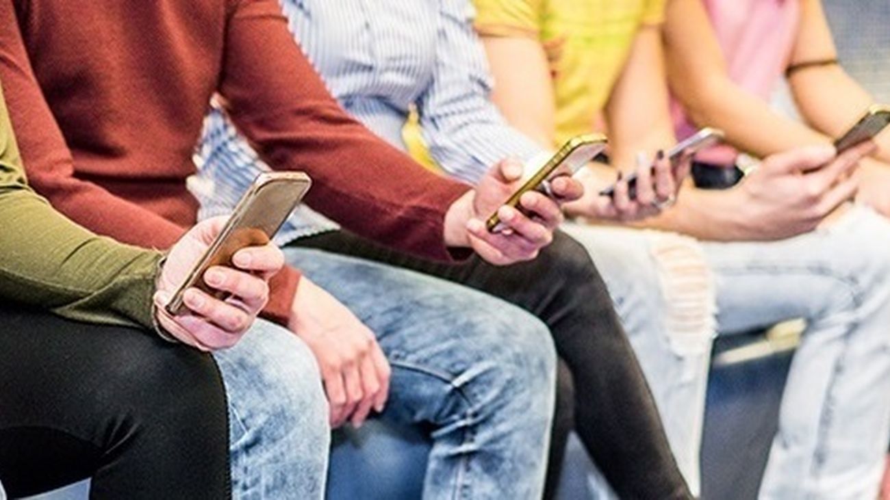 Un grupo de jóvenes usa sus teléfonos móviles