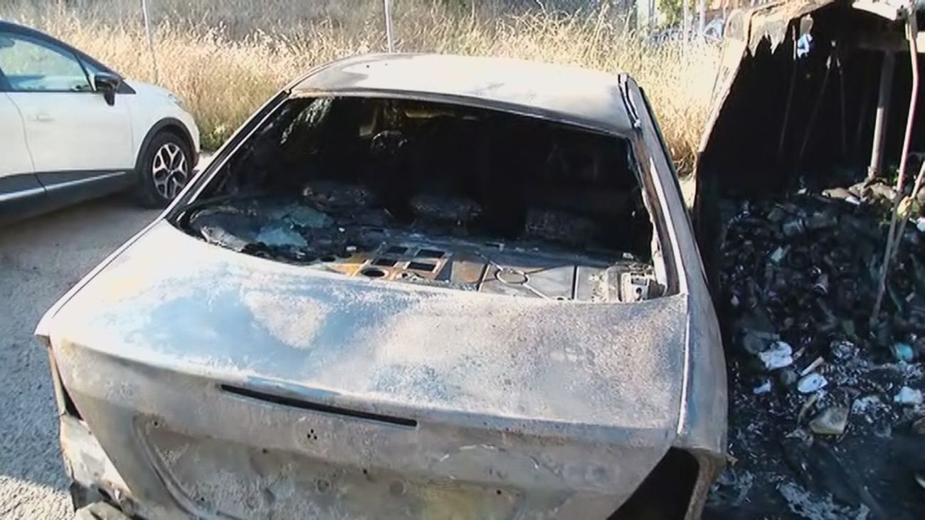Un coche queda calcinado tras la quema de un contenedor cercano en Hortaleza