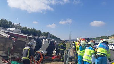 Los bomberos rescatan al conductor de un camión atrapado tras volcar en la M-50