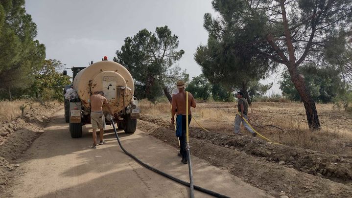 El tractor avanza con el depósito de agua mientras los voluntarios llevan las mangueras hasta los árboles / ENTORNO MEAQUES RETAMARES