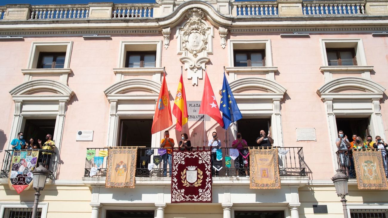 Las peñas cuelgan sus estandartes y pañoletas en la fachada del Ayuntamiento de Alcalá para dar comienzo a las fiestas
