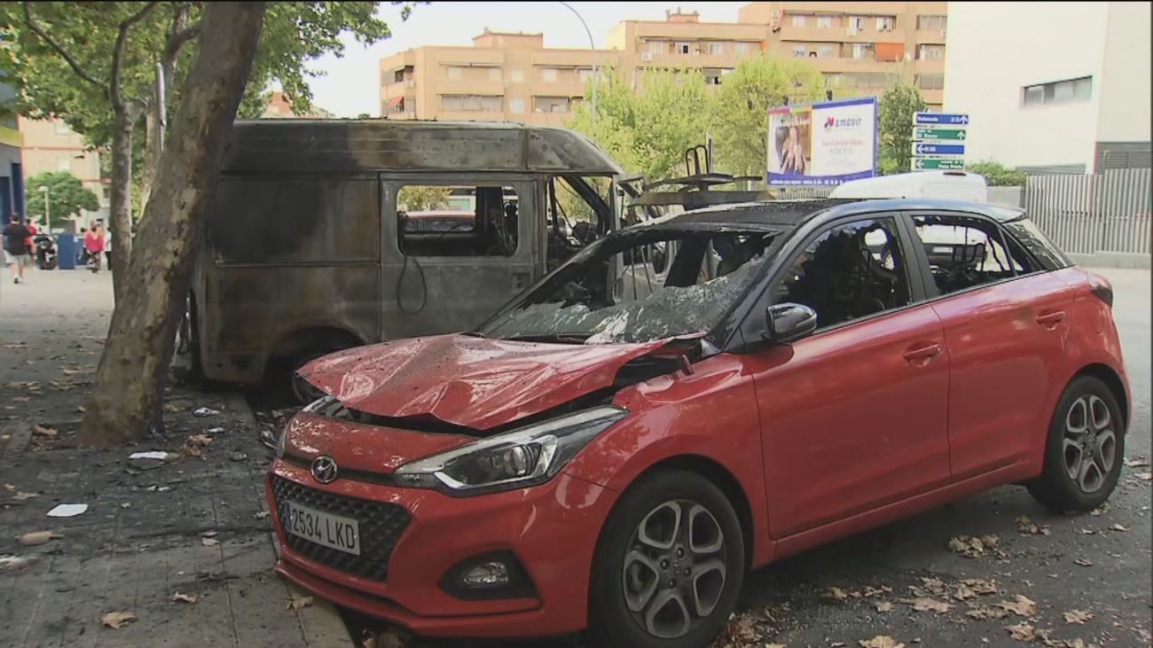 Coches calcinados tras la quema vandálica de contenedores en Puente de Vallecas
