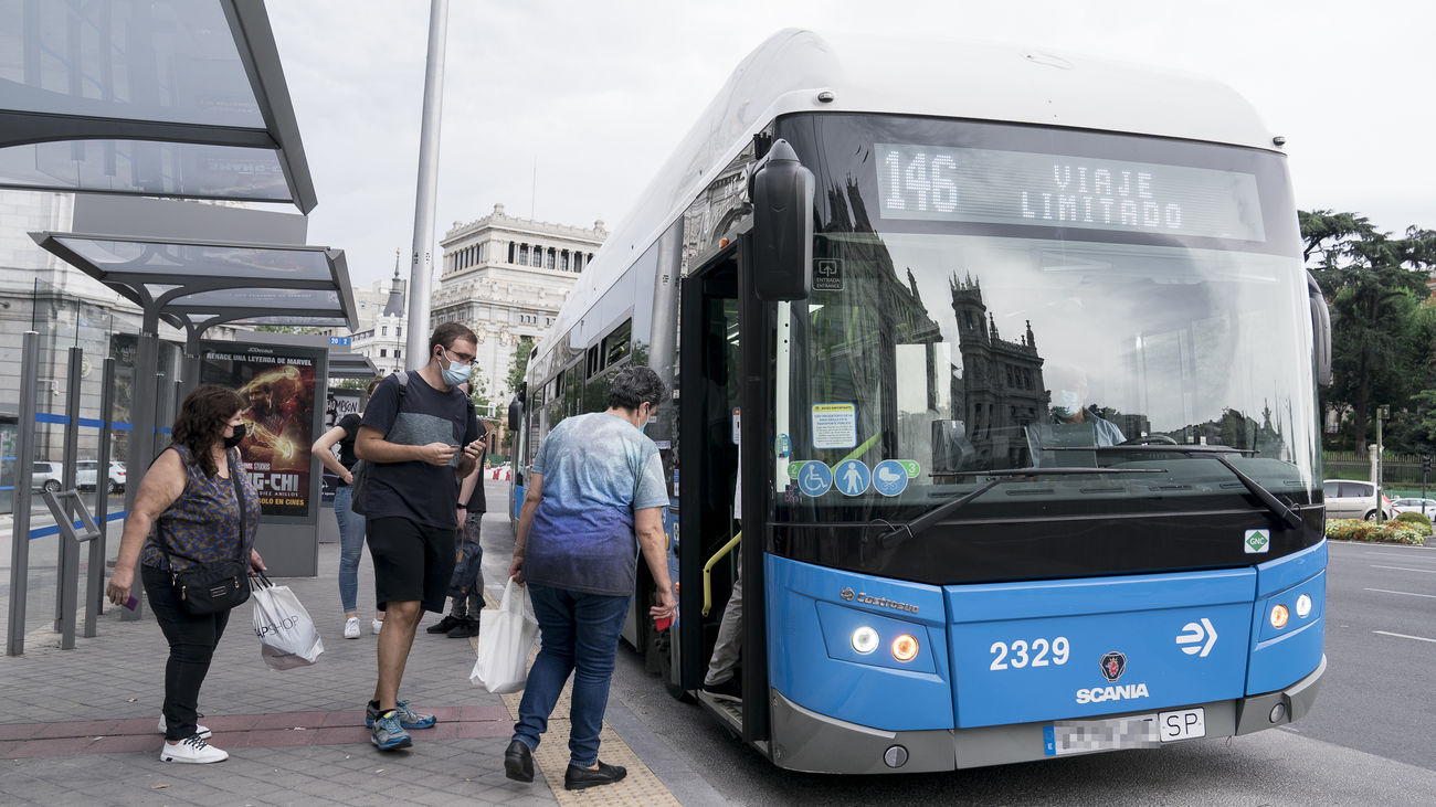 Varias personas suben un autobús de la EMT en la Plaza de Cibeles