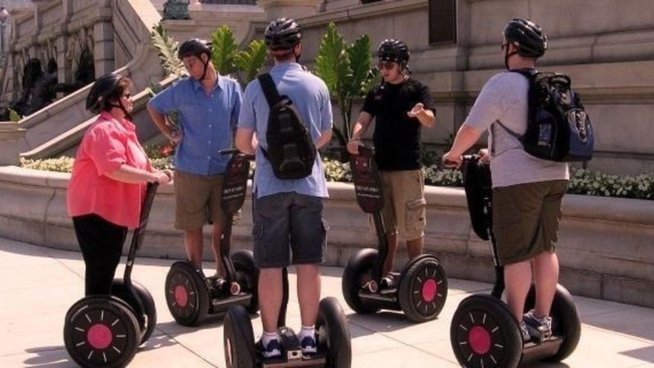 Un grupo de turistas con vehículos eléctricos individuales sobre una acera