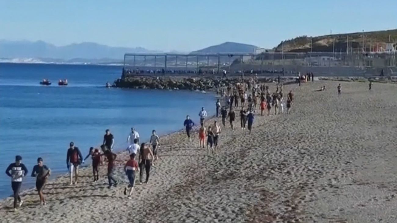 Un grupo de personas camina por la playa tras entrar a Ceuta