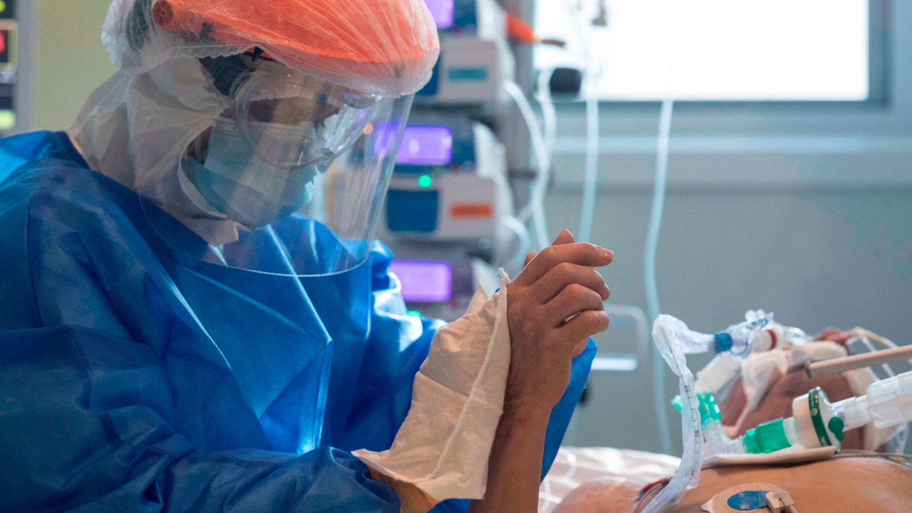 Un sanitario con traje de protección atiende a un paciente de covid intubado
