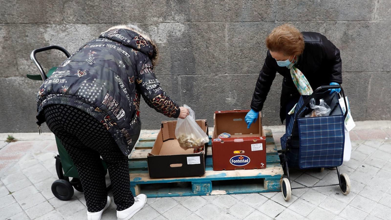 Dos mujeres recogen productos donados por una despensa solidaria de Madrid