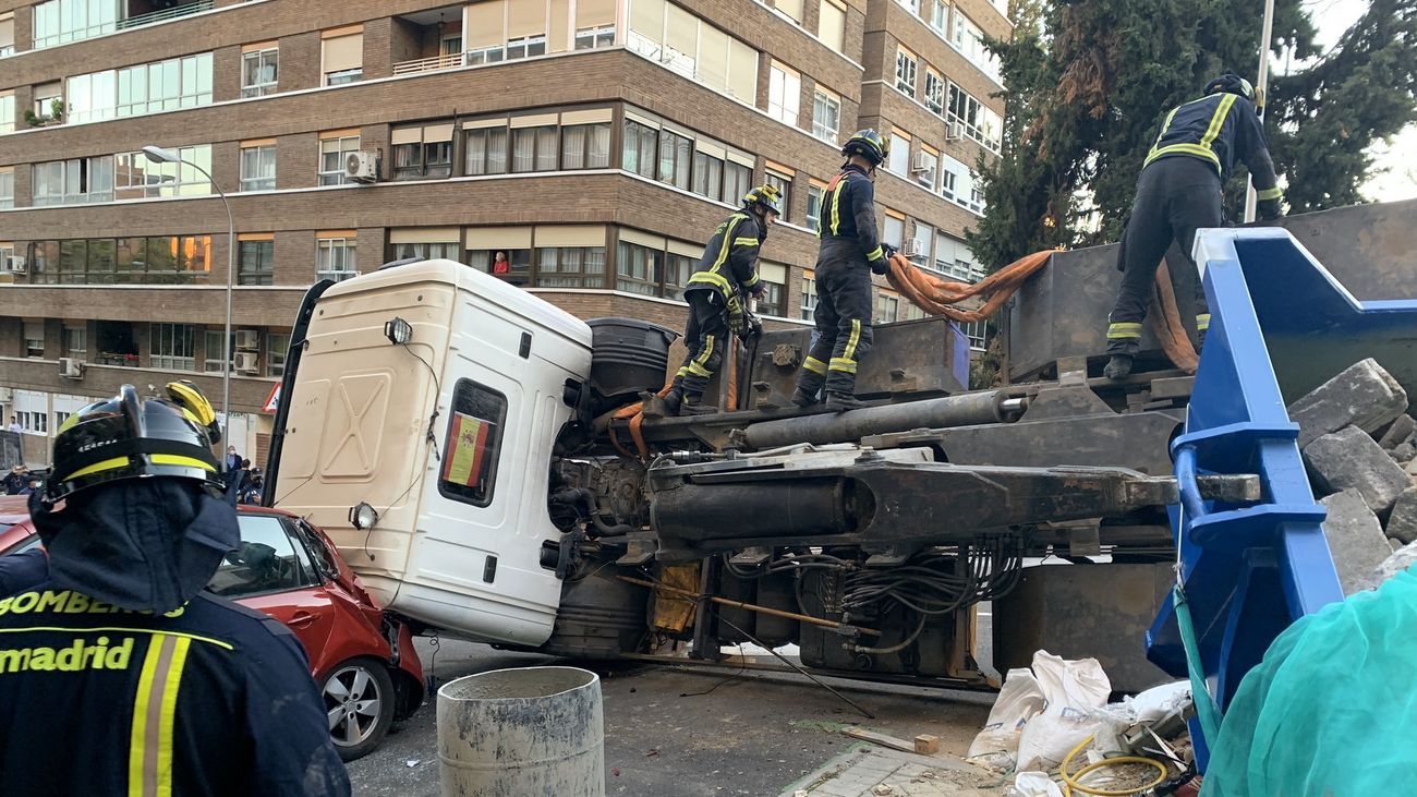 Bomberos del Ayuntamiento de Madrid trabajando sobre el camión volcado