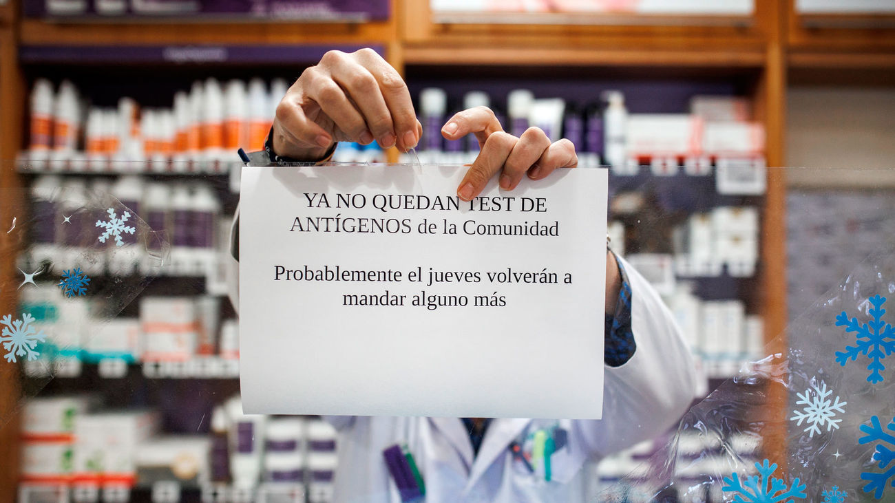 Un farmacéutico cuelga el cartel anunciando que los test de antígenos de la Comunidad de Madrid están agotados