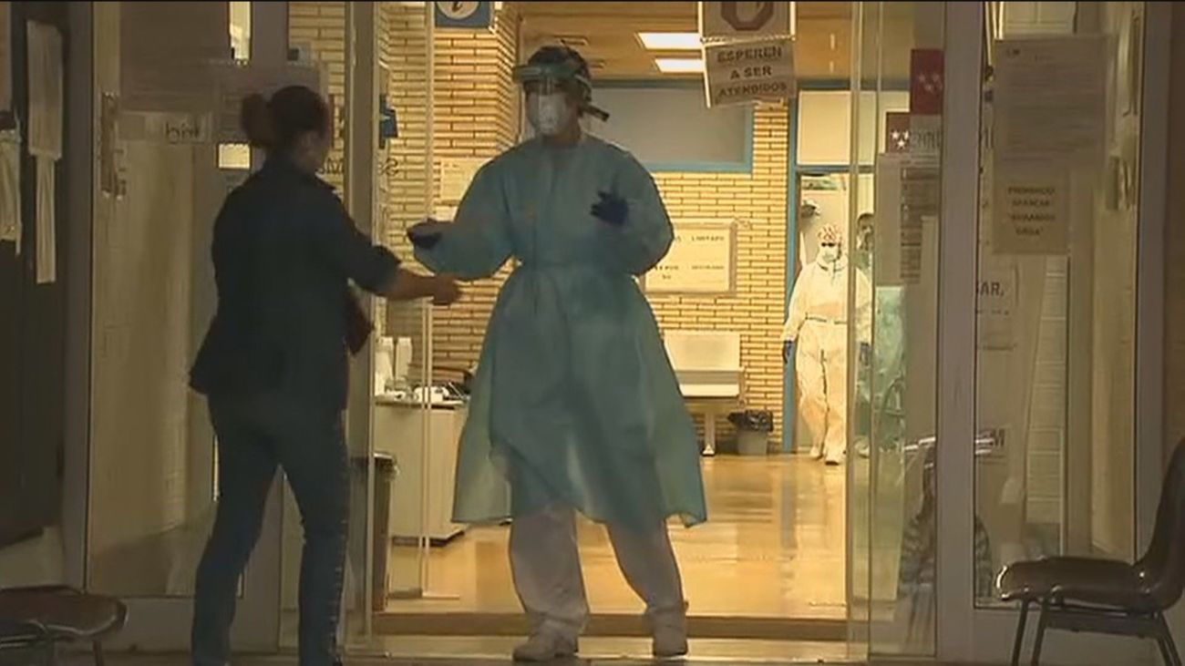 Un sanitario entrega un documento a una paciente a la puerta del centro de salud