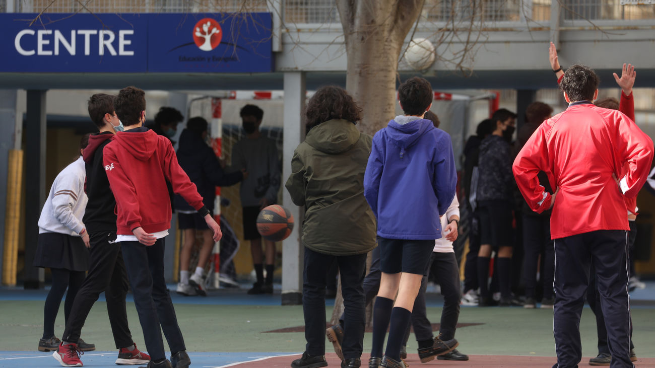 Un grupo de niños juegan al baloncesto en el patio del colegio
